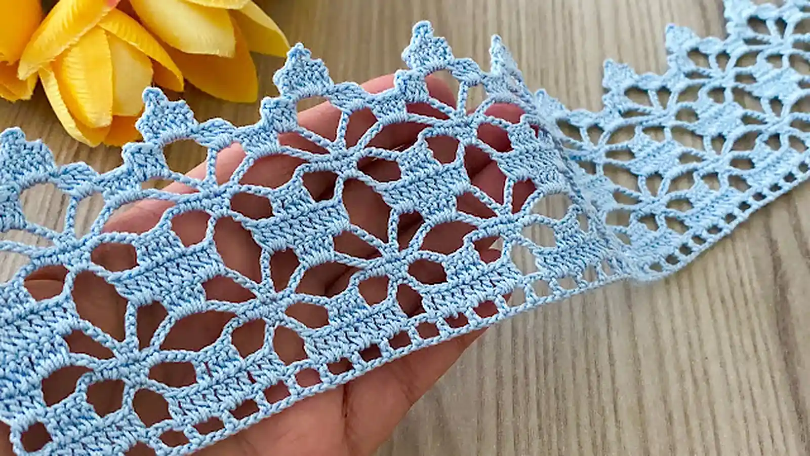 Puntilla calada azul tejida a crochet con motivos florales.