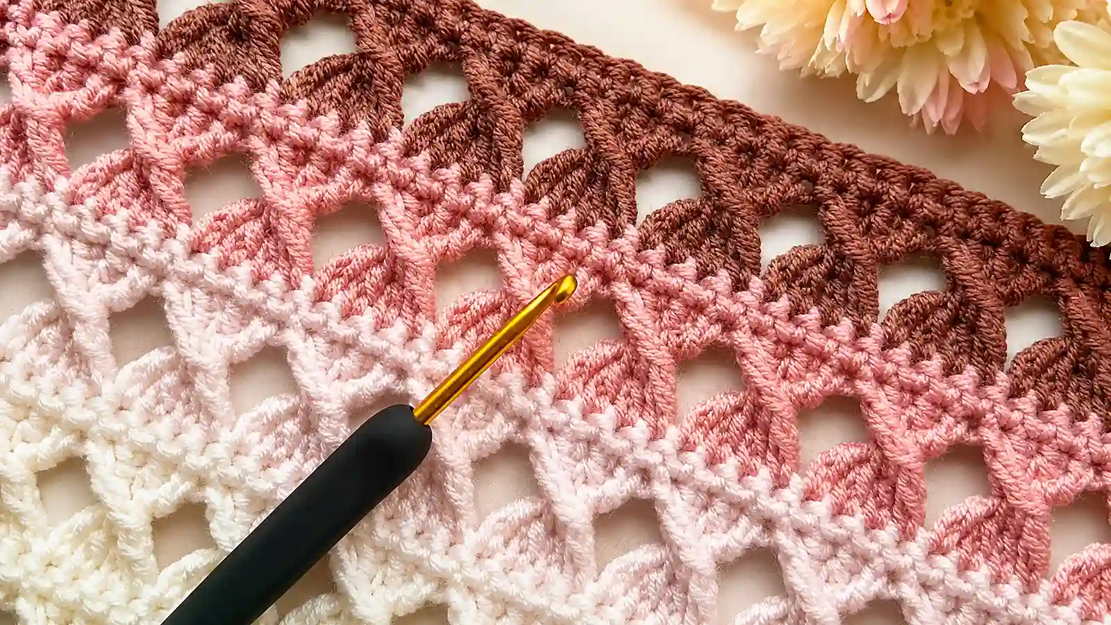 Muestra de tejido a crochet en tonos rosa y marrón con textura calada.