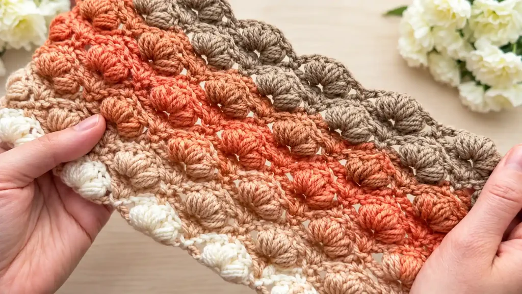 Punto tipo concha fácil para blusas a crochet Muestra de punto bobble a crochet en tonos crema, coral y beige.