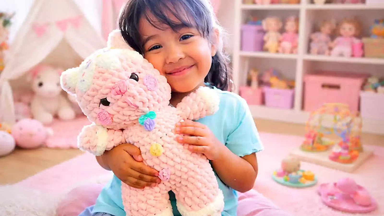 Niña abrazando un tierno amigurumi rosa tejido a crochet.