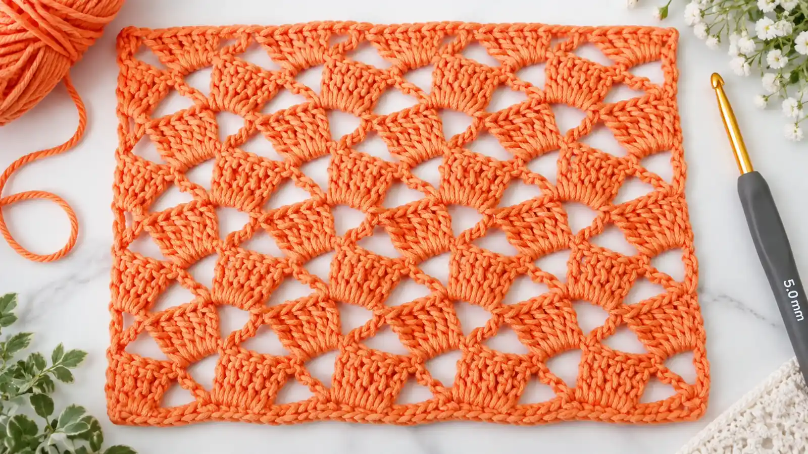Muestra de punto fantasía naranja tejida a crochet con diseño calado.